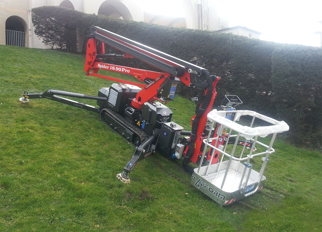 Spider lift in a green park setting with a worker operating it