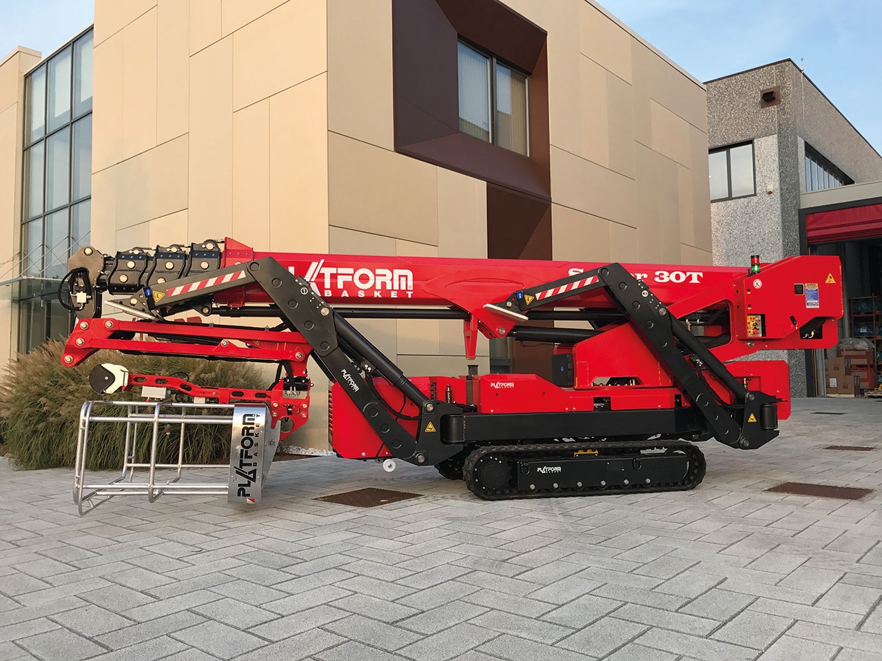 Spider lift parked outside a modern building.